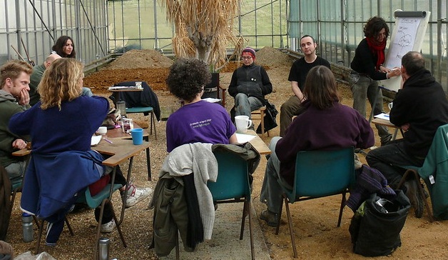 OrganicLea co-op members seated in a circle in front of one member who is writing on a whiteboard