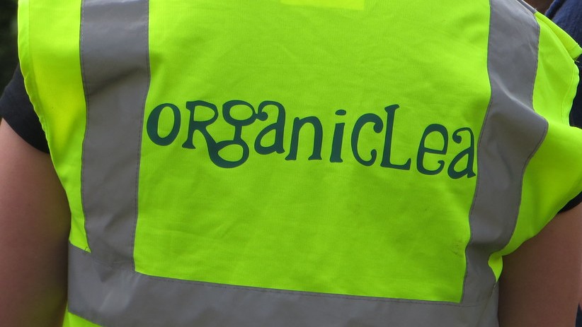 Close-up of OrganicLea logo on back of hi-vis jacket
