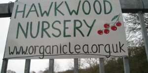 Large sign on metal gate displaying Hawkwood Nursery with www.organiclea.org.uk underneath