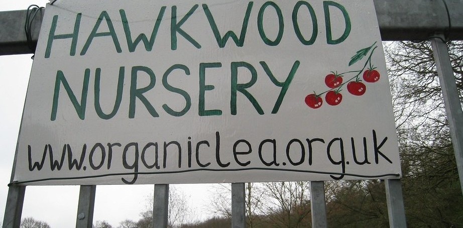Large sign on metal gate displaying Hawkwood Nursery with www.organiclea.org.uk underneath
