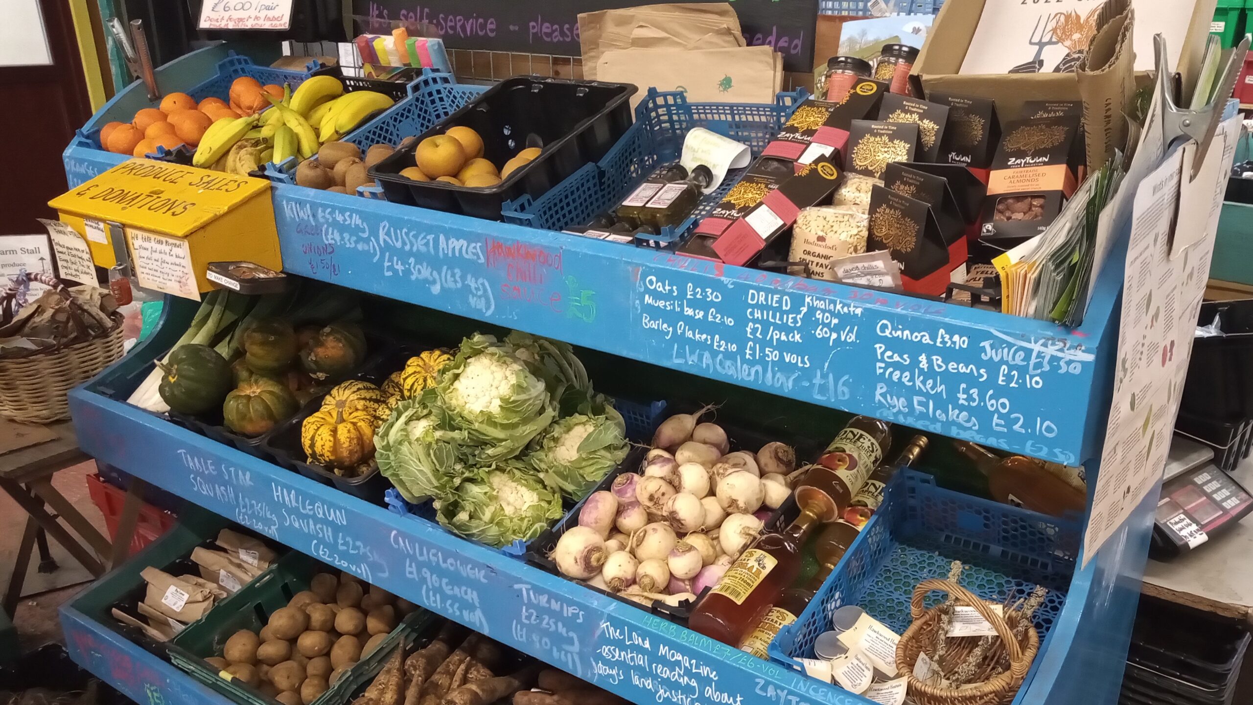 A range of fresh produce displayed in baskets on the OragnicLea Farm Stall including cauliflower, potatoes, apples and squash