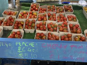 Close-up of a shelf holding rows of punnets containing ripe red cherry tomatoes.